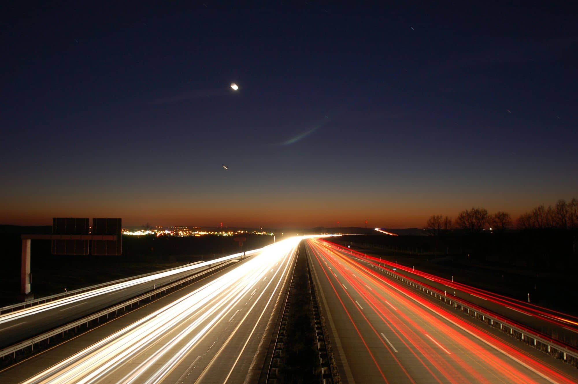 Light trails of traffic on a highway at dusk.